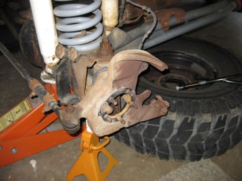 1995 Ford Bronco - Close-up of a vehicle's front suspension components, including a ball joint assembly and tire.