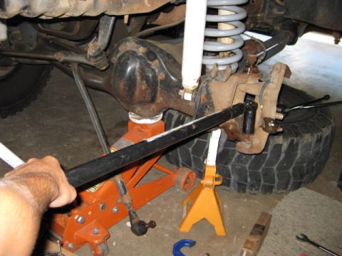 1995 Ford Bronco - Close-up view of a vehicle's front suspension ball joint area, supported by a jack and jack stands.