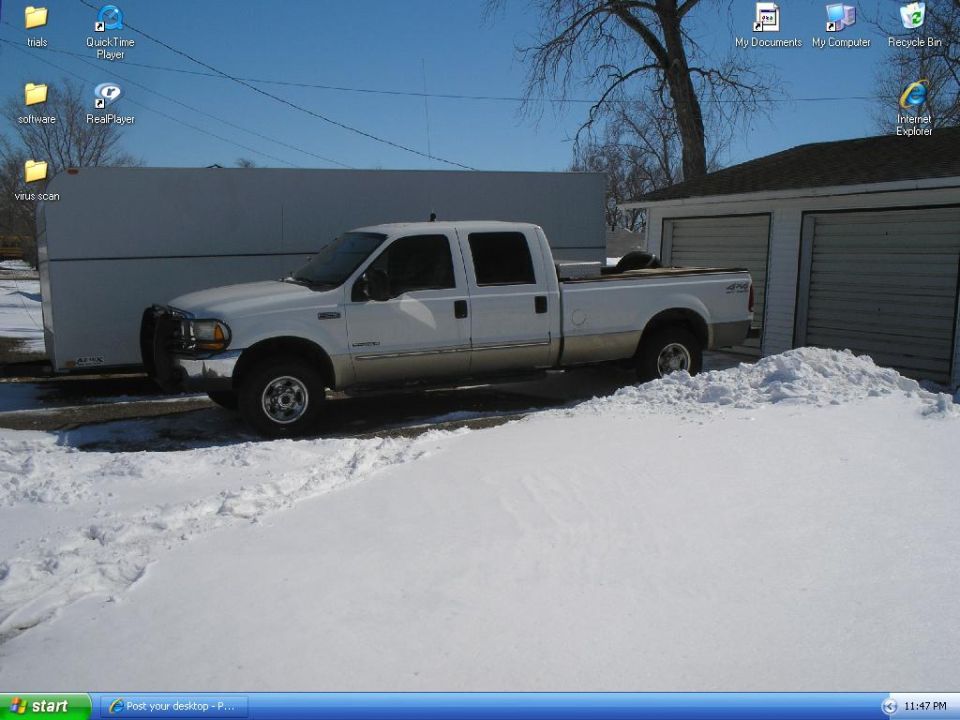 White 2000 Ford F-250 crew cab pickup truck parked in snow next to a garage