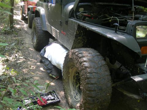 1991 Jeep Wrangler - A person works on a 1991 Jeep Wrangler on a dirt trail, with another Jeep following.