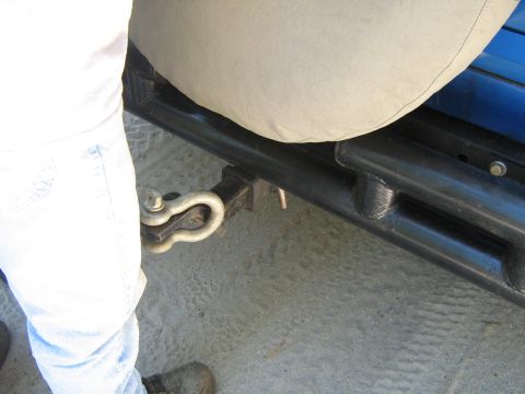 1990 Ford Bronco - Close-up of a trailer hitch receiver and shackle, with a person's legs in the frame.