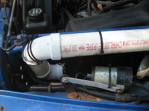 1990 Ford Bronco - Custom piping is installed in the engine bay of a blue vehicle.