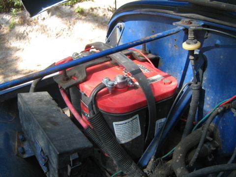 1990 Ford Bronco - Close-up of a red Optima car battery secured in a blue engine compartment.