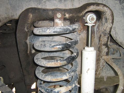 1990 Ford Bronco - Close-up of a vehicle's front suspension system, showing a coil spring and shock absorber.
