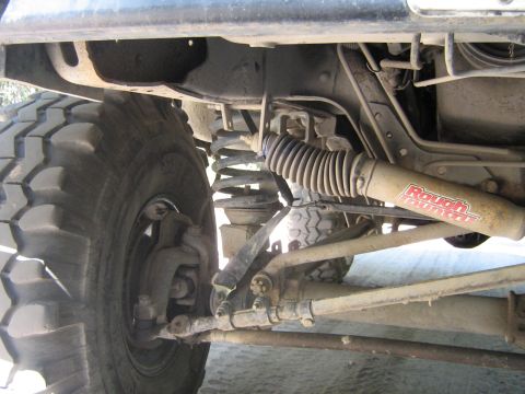 1990 Ford Bronco - Underside view of a vehicle's suspension system, showing a large tire and shock absorber.