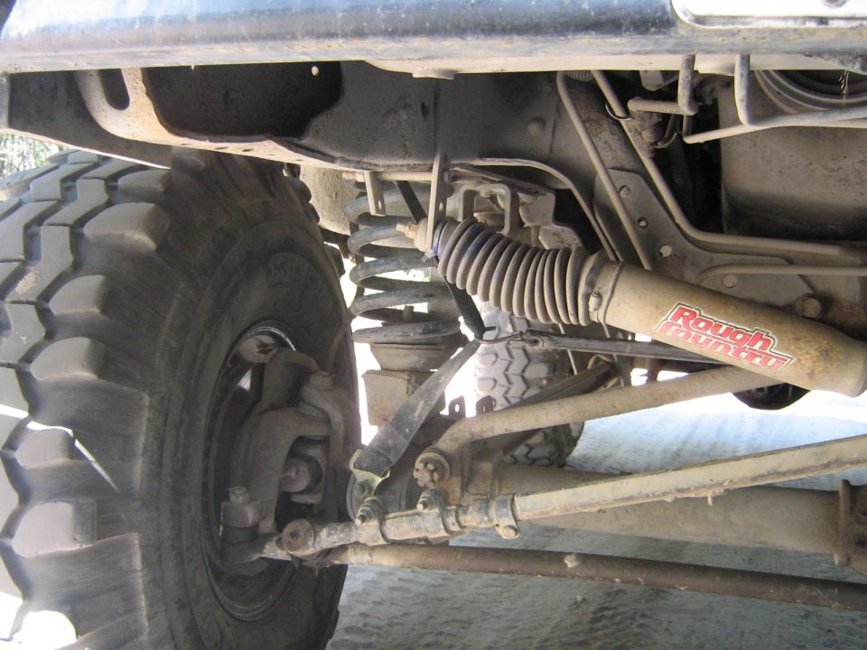 Close-up of a large off-road tire and suspension components, including a Rough Country shock absorber