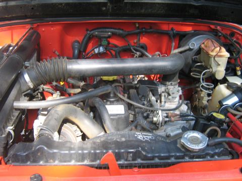 1990 Ford Bronco - Close-up view of a vehicle's engine bay, showing various mechanical parts and hoses.