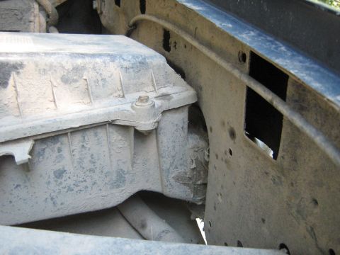 1990 Ford Bronco - Dusty engine bay component with visible metal brackets and hoses.