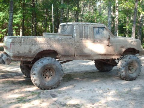 1990 Ford F-150 - A heavily mud-covered Ford pickup truck with an extended cab shown in side profile, lifted high on oversized off-road tires with steel whee…
