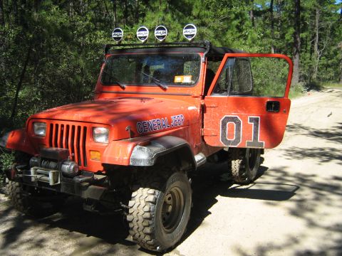1990 Ford Bronco - This orange Jeep Wrangler has "General Jeep" and "01" decals, suggesting a custom modification rather than a specific model year.