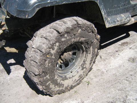 1990 Ford Bronco - This vehicle's tire and fender are heavily caked with mud, suggesting off-road use.