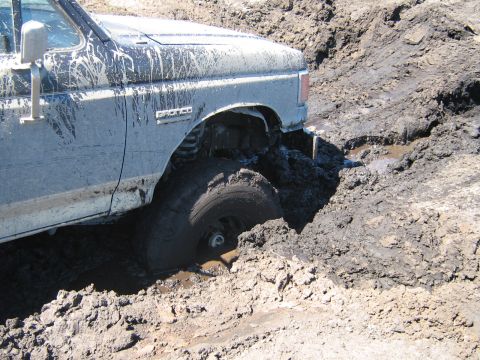1990 Ford Bronco - This 1990 Ford Bronco is stuck in thick mud, with the front wheel almost completely covered.