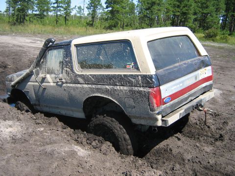 1990 Ford Bronco - This 1990 Ford Bronco is deeply stuck in thick mud, with a snorkel attached and a tow strap connected to the rear bumper.