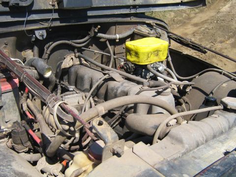1990 Ford Bronco - The engine compartment of a vehicle shows various mechanical components and hoses, with a watermark at the bottom right.