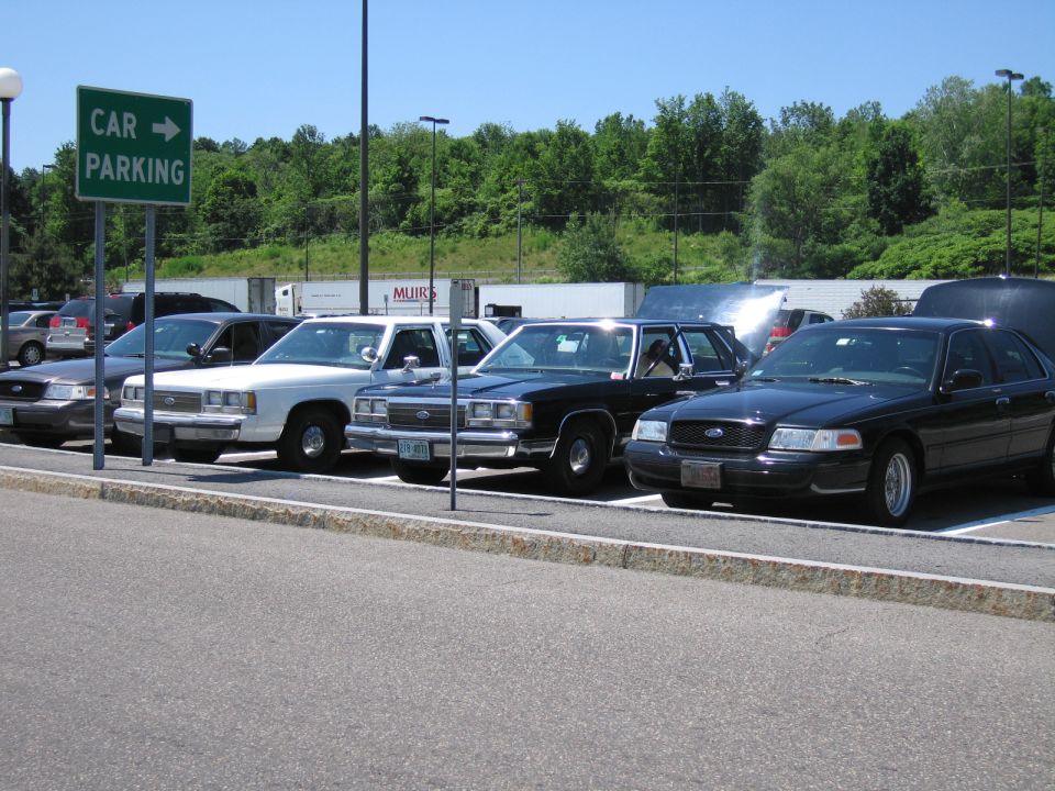 Four Ford Crown Victoria police cars parked in a lot, one with hood open