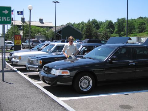 2001 Ford Crown Victoria - Several Ford Crown Victorias are parked in a lot on a sunny day.