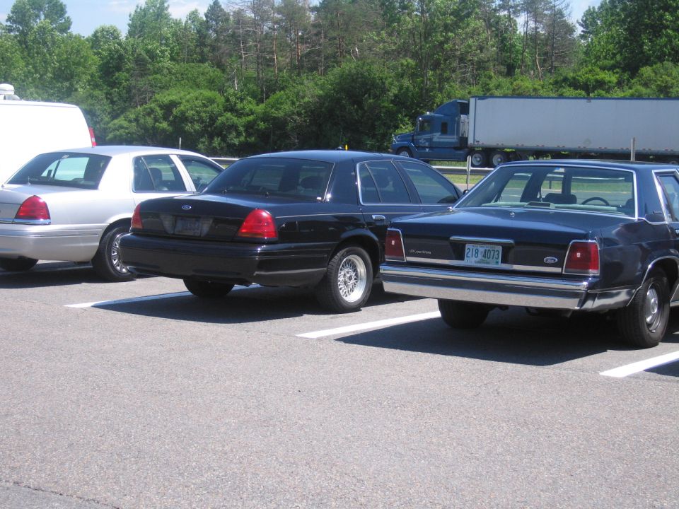 Rear view of a black 2001 Ford Crown Victoria parked next to two others