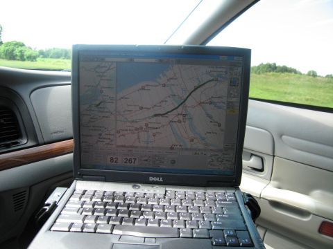 2001 Ford Crown Victoria - A laptop displaying a map is mounted on the dashboard of a vehicle, with a view of the exterior through the window.