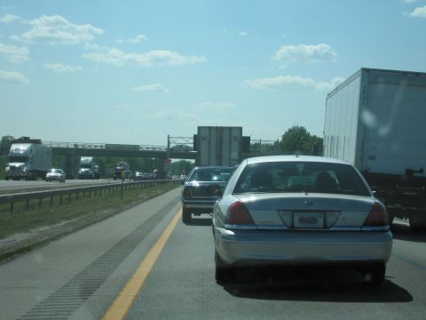 2001 Ford Crown Victoria - A silver 2001 Ford Crown Victoria is seen from behind on a highway, with other vehicles around it.