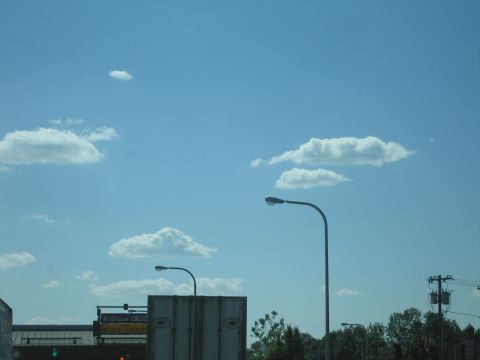 2001 Ford Crown Victoria - A daytime scene with a bright blue sky, fluffy clouds, and streetlights.
