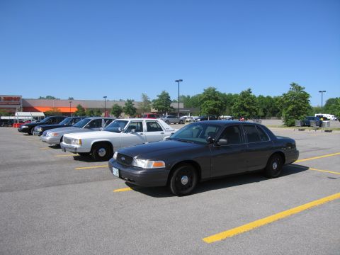 2001 Ford Crown Victoria - Several Ford Crown Victorias are parked in a lot on a sunny day.