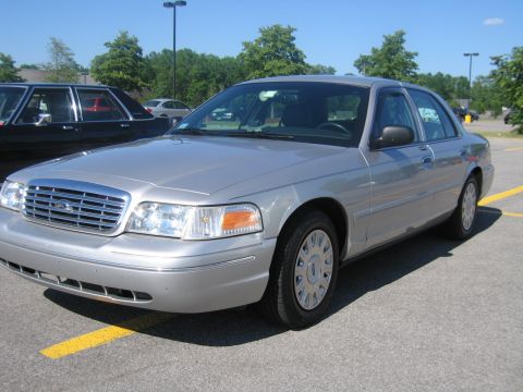 2001 Ford Crown Victoria - A silver sedan is parked in a lot with a dark vehicle to its left.