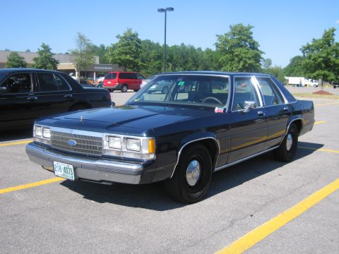 2001 Ford Crown Victoria - This dark blue sedan is parked in a lot, with another vehicle visible to the left.