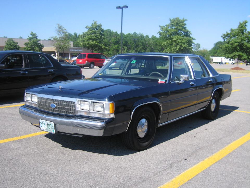 Dark blue sedan, front 3/4 view, parked in a lot. License plate 218-4073