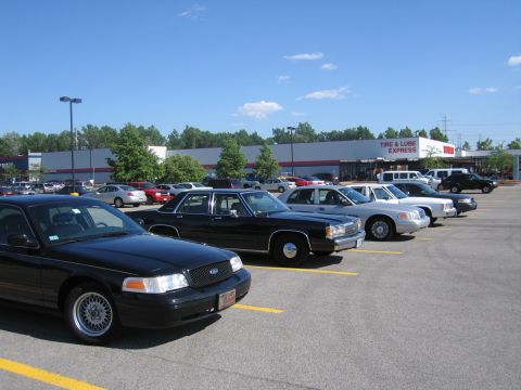 2001 Ford Crown Victoria - A line of Ford Crown Victoria police cars are parked in a lot outside a Tire & Lube Express store.