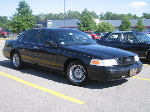 2001 Ford Crown Victoria - A black 2001 Ford Crown Victoria is parked in a lot with yellow lines.
