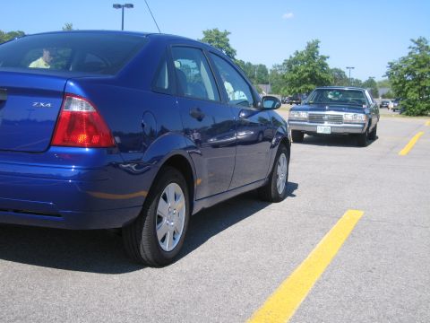 2001 Ford Crown Victoria - A blue Ford Focus sedan is parked in a lot, with another vehicle visible in the background.