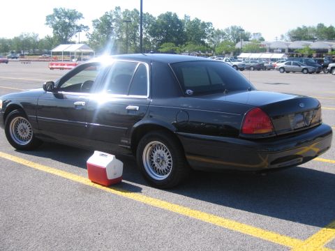 2001 Ford Crown Victoria - A black sedan is parked in a lot, with a red and white cooler beside it.