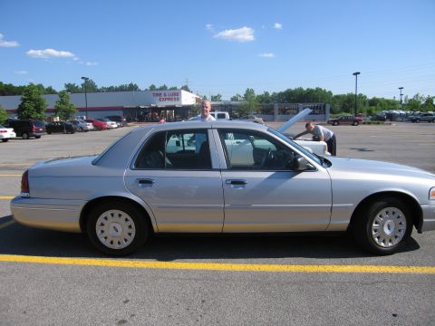 2001 Ford Crown Victoria - Silver 2001 Ford Crown Victoria parked in a lot, with people near another car with its hood up.