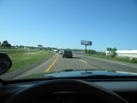 2001 Ford Crown Victoria - Driving on a sunny day with traffic ahead and billboards visible along the highway.