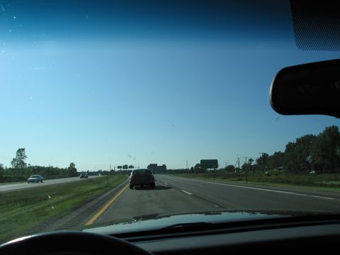 2001 Ford Crown Victoria - View from inside a vehicle driving on a highway with other cars on the road under a clear blue sky.