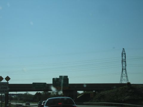 2001 Ford Crown Victoria - Driving on the highway with overhead signs and power lines visible against a clear blue sky.