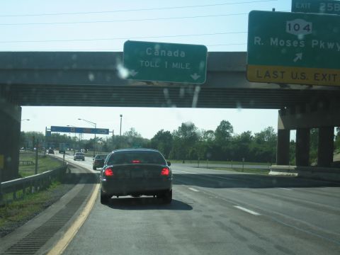 2001 Ford Crown Victoria - A dark sedan, identified as a 2001 Ford Crown Victoria, travels on a highway under an overpass.