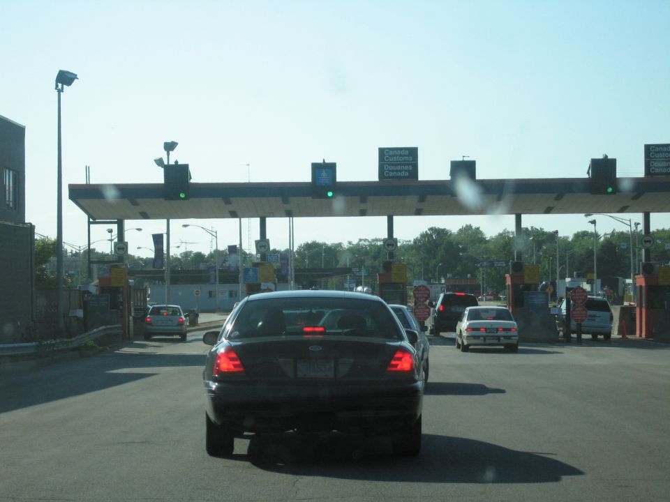 Black 2001 Ford Crown Victoria at a border crossing, rear view. License plate is partially visible