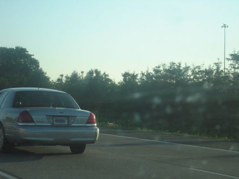 2001 Ford Crown Victoria - Rear view of a silver 2001 Ford Crown Victoria sedan on a highway under a clear sky.