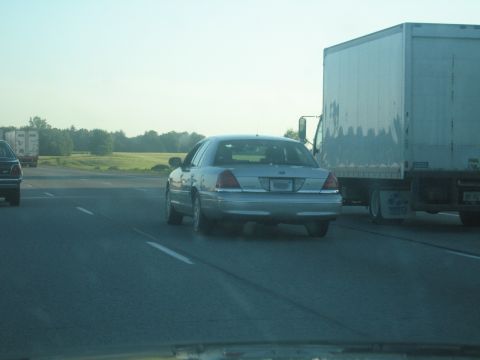 2001 Ford Crown Victoria - A silver 2001 Ford Crown Victoria travels on the highway next to a large truck.