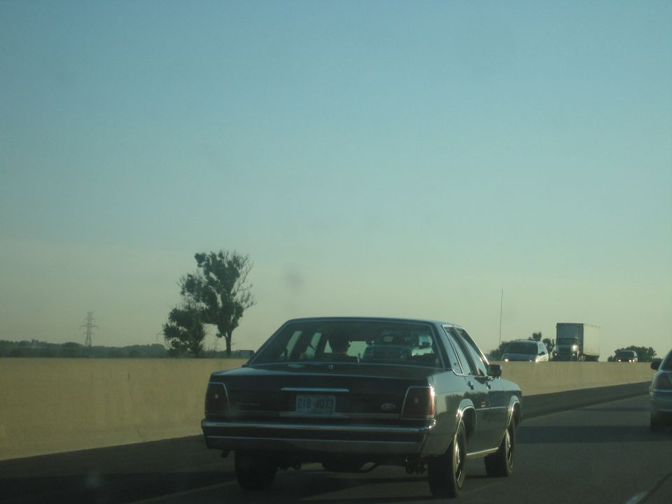 Rear view of a dark Ford Crown Victoria driving on a highway