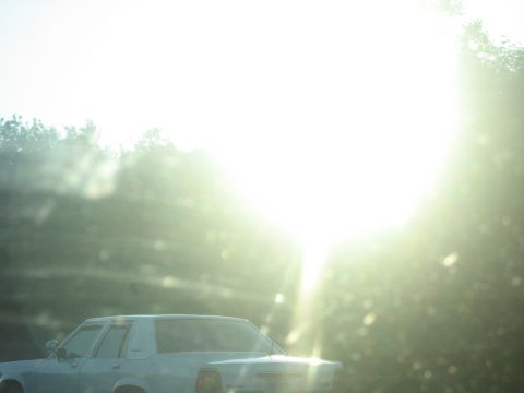 2001 Ford Crown Victoria - A light blue sedan is seen from the rear, with the sun glaring brightly in the background.