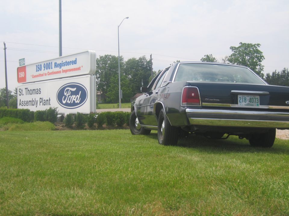 Dark green 2001 Ford Crown Victoria parked in front of a Ford St. Thomas Assembly Plant sign