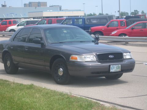 2001 Ford Crown Victoria - A dark gray 2001 Ford Crown Victoria is parked in front of a row of other vehicles.