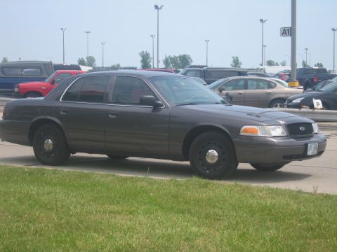 2001 Ford Crown Victoria - A dark gray 2001 Ford Crown Victoria sedan is parked in a lot with other vehicles.