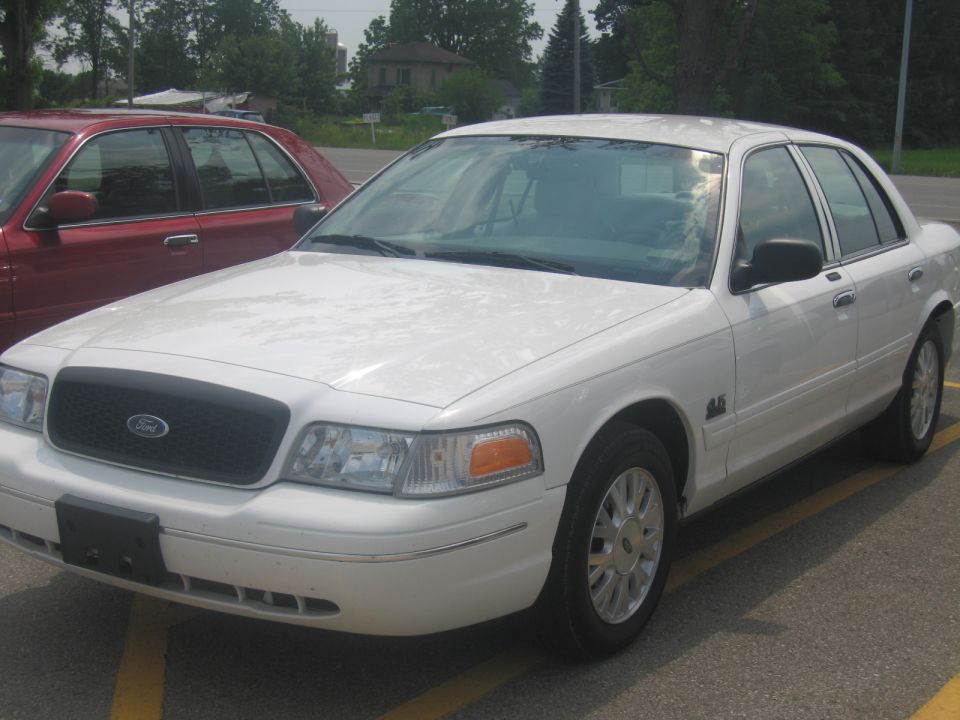 White 2001 Ford Crown Victoria parked next to a red car