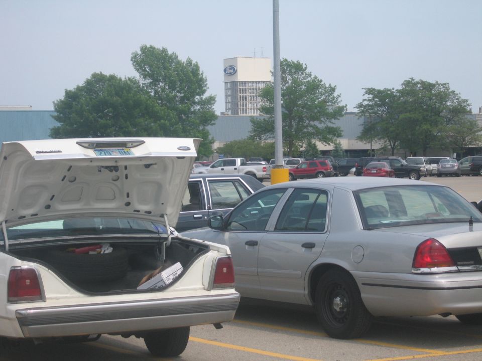 Silver 2001 Ford Crown Victoria parked in a lot, trunk open on a white car in foreground