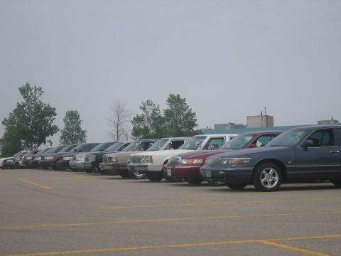 2001 Ford Crown Victoria - Multiple 2001 Ford Crown Victorias are parked in a lot under an overcast sky.