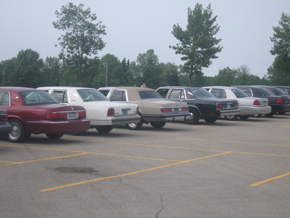 Side view of a maroon sedan, white sedan, tan sedan, and black sedan parked in a lot