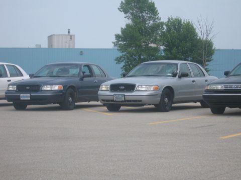 2001 Ford Crown Victoria - Two Ford Crown Victorias are parked side-by-side in a parking lot.